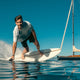 Rider on a LIND electric surfboard next to a sailing yacht
